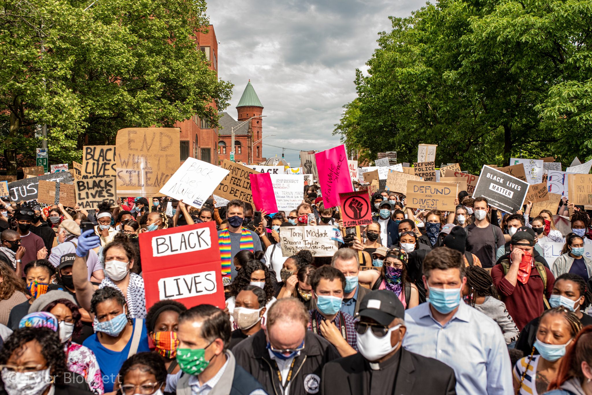The march fills the street from curb to curb, a sign held over nearly every head.