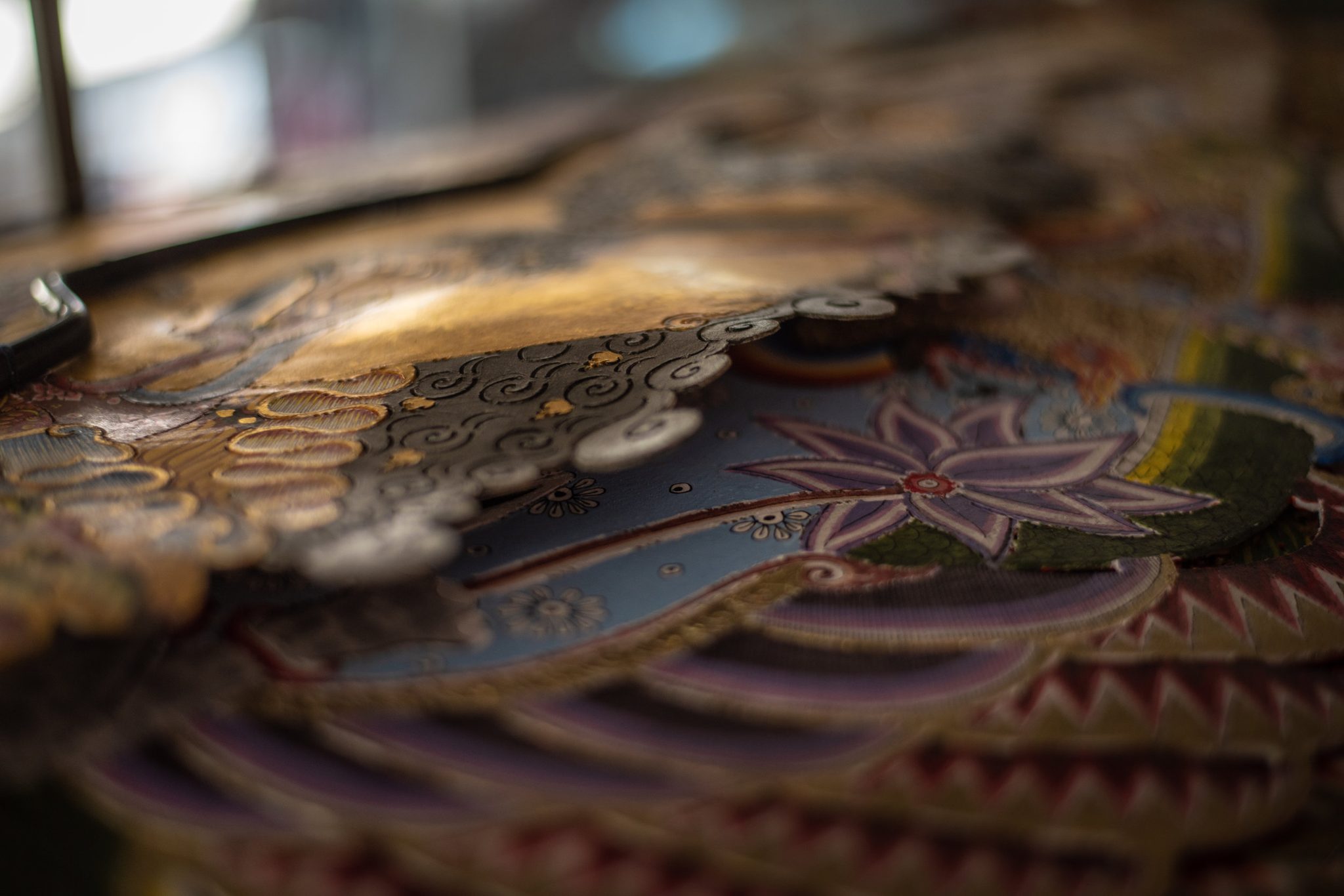 Up close, the gold and the painted petals catch the window light.