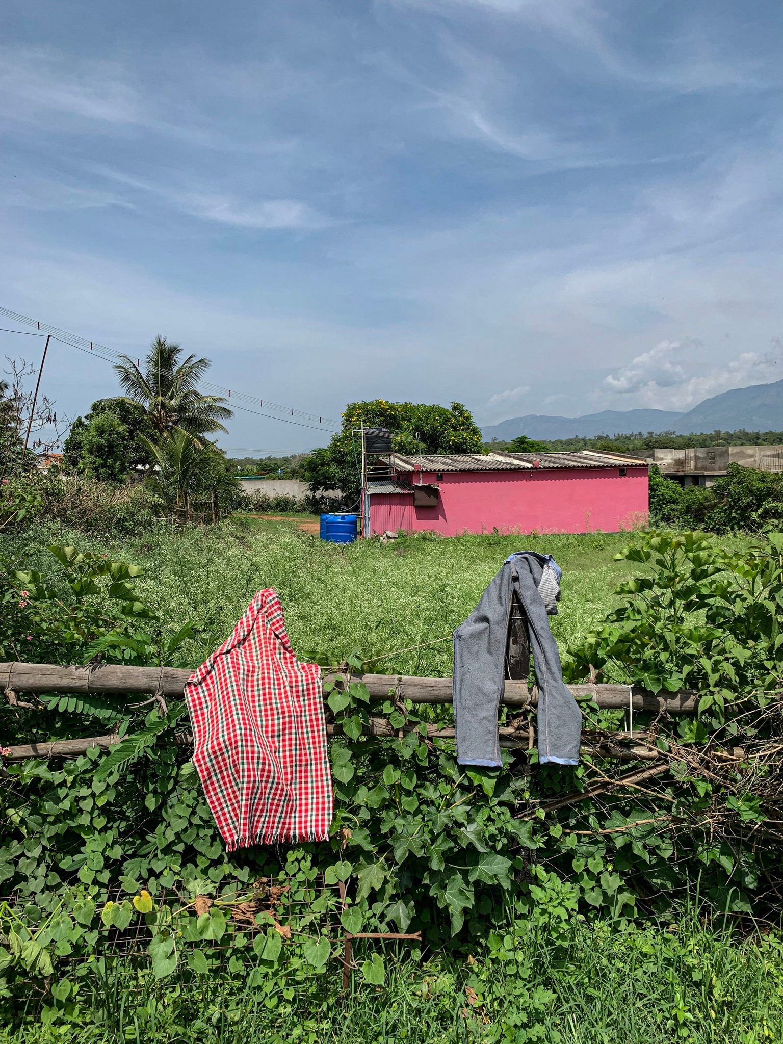 Laundry dries on a fence in front of a pink house and the hills.
