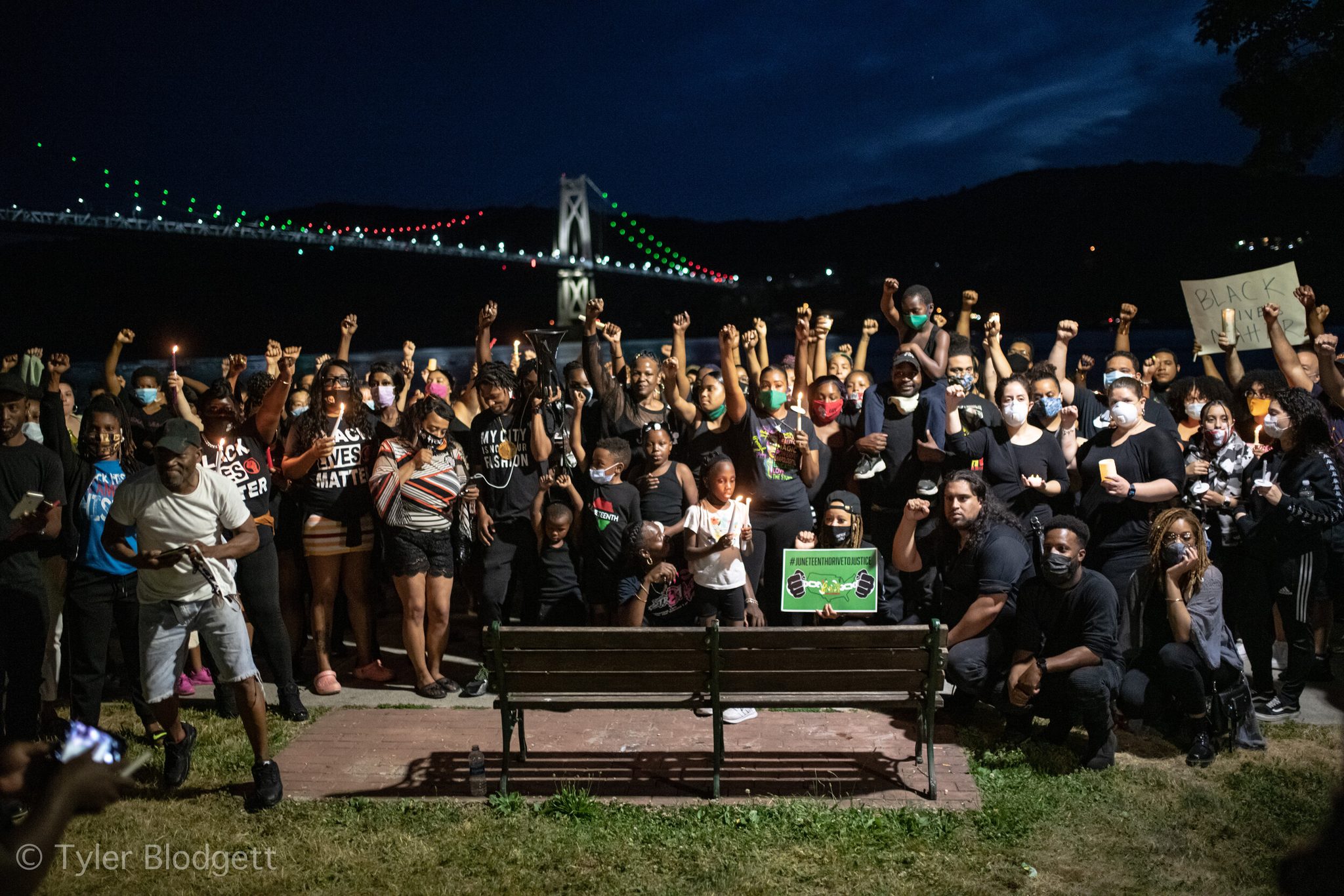 Fists raised, the whole crowd gathers for one picture beneath the lit Mid-Hudson Bridge.