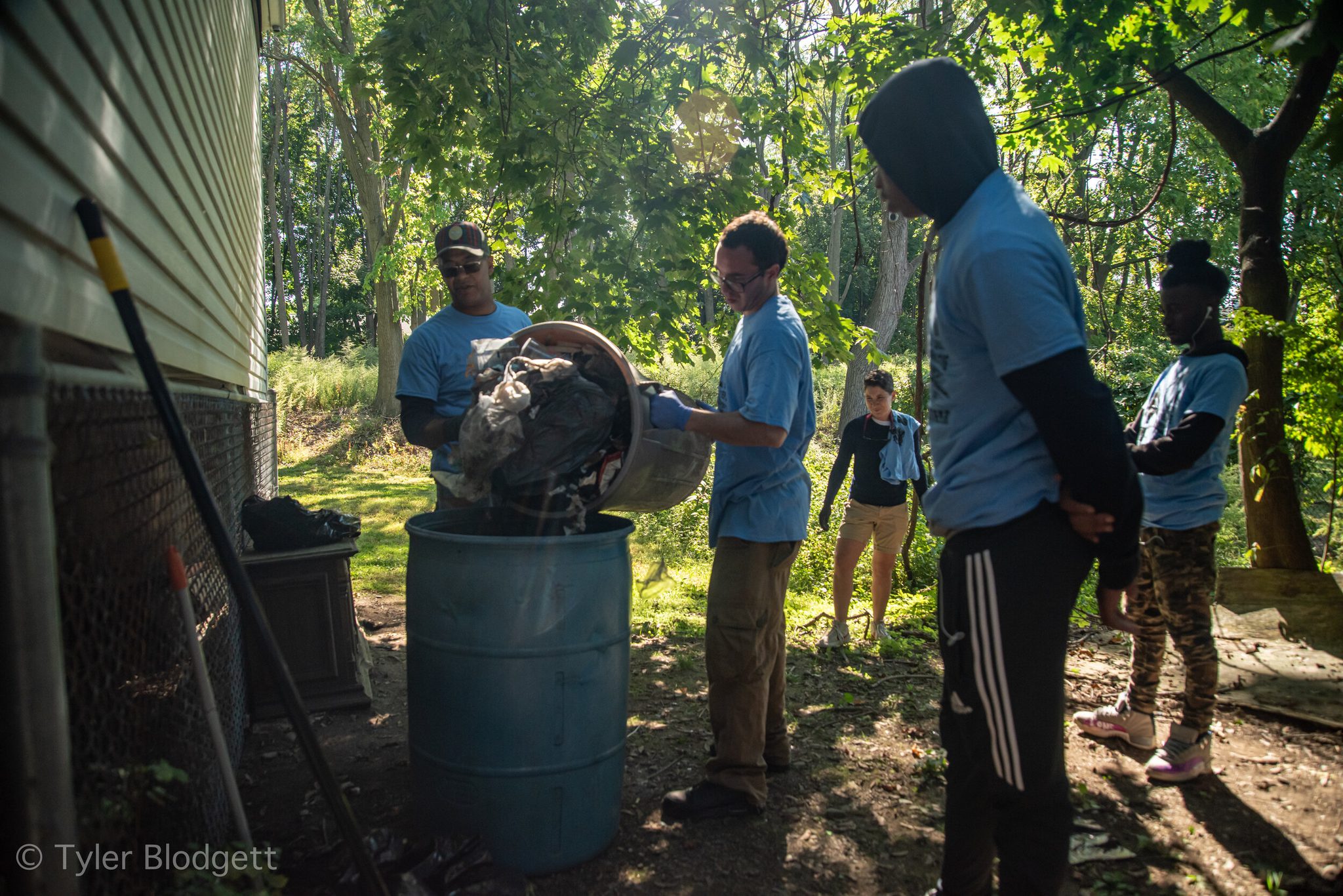 Volunteers in matching blue shirts empty their buckets into a barrel during the cleanup.