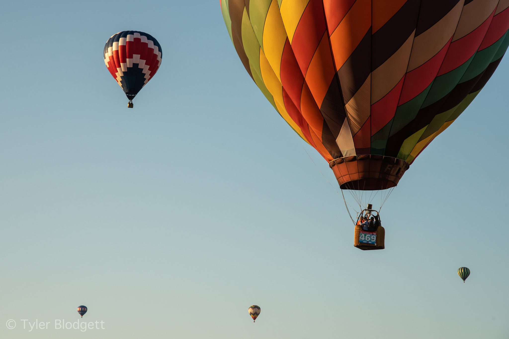 Balloons scatter across the evening sky, the nearest close enough to read its number.