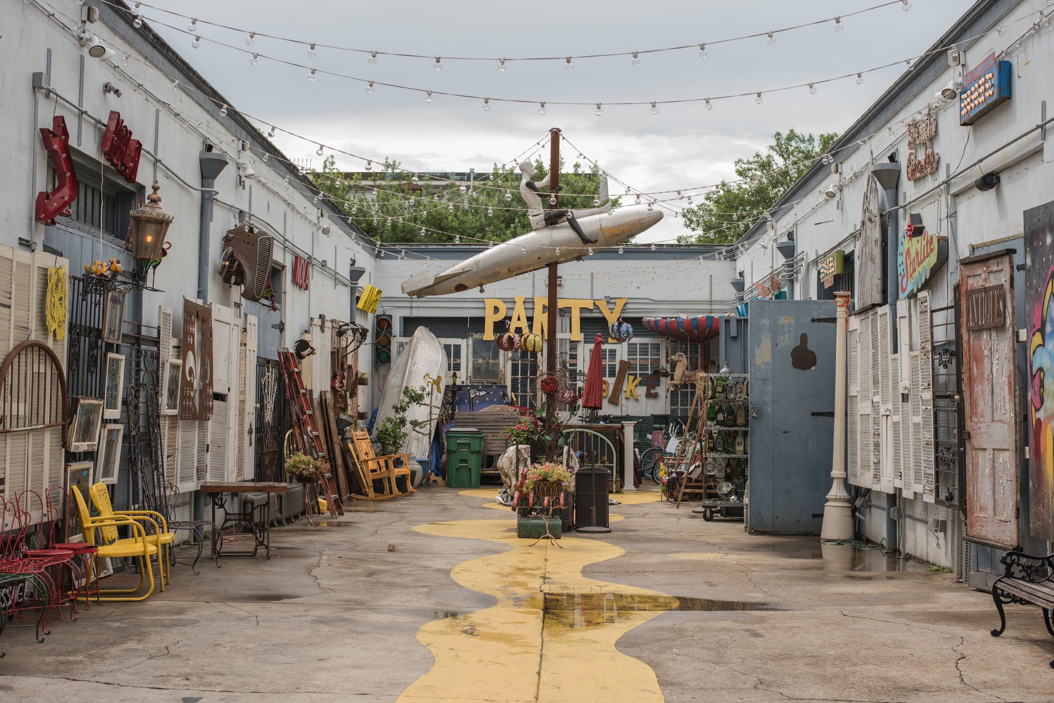 A painted river runs down the middle of a courtyard hung with shutters, signs and a canoe.
