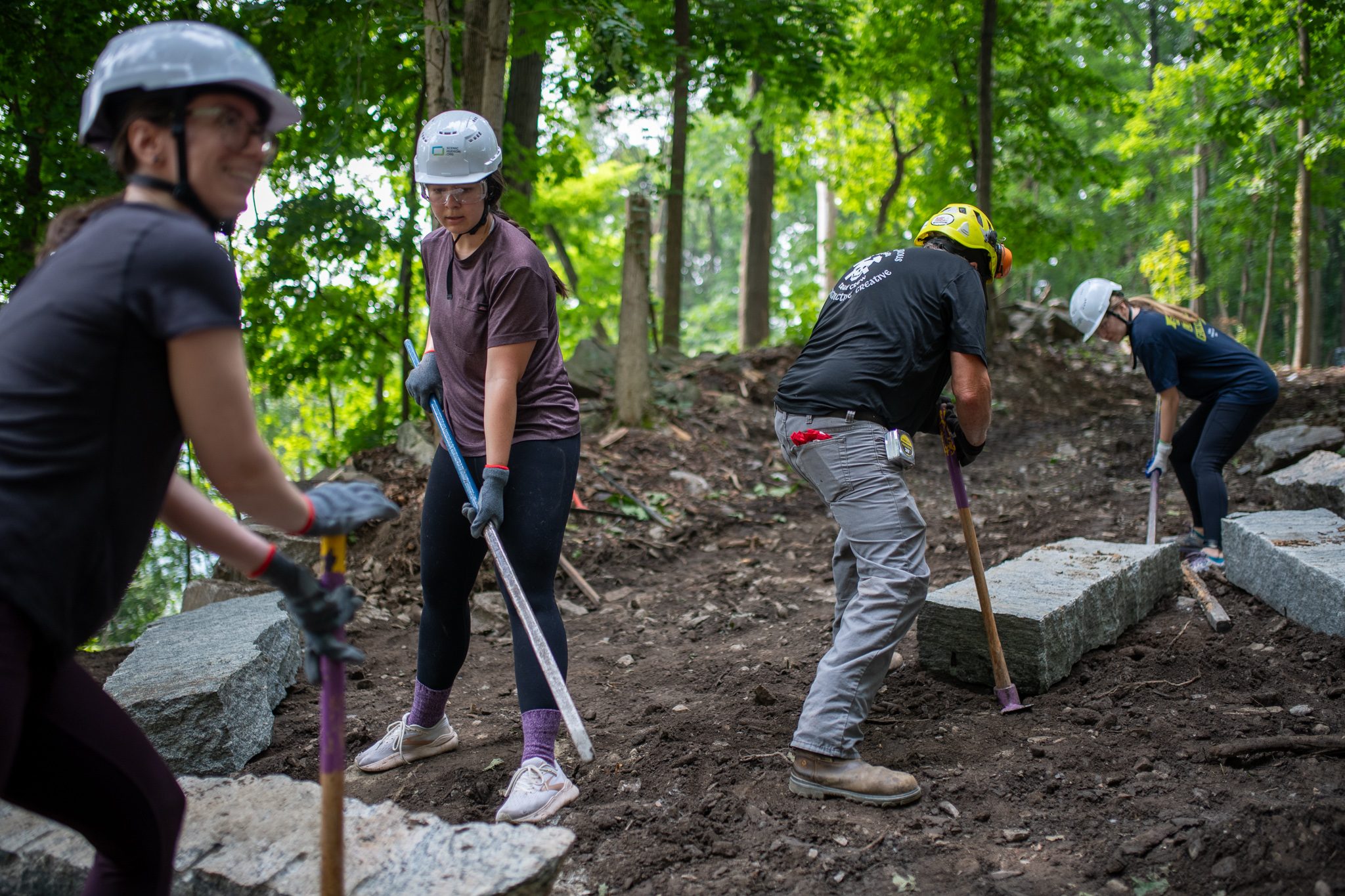 Bars dug in, the crew works the stone into position on the slope.
