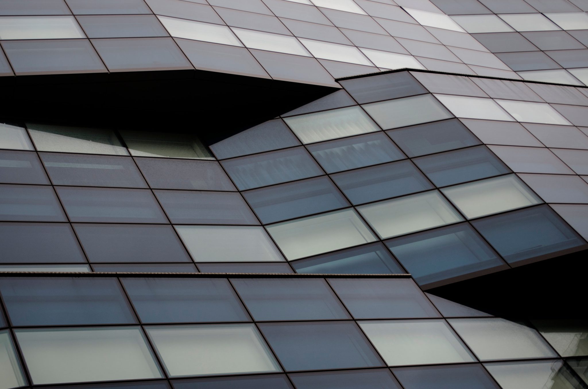Panes of glass fold and buckle across an undulating facade.