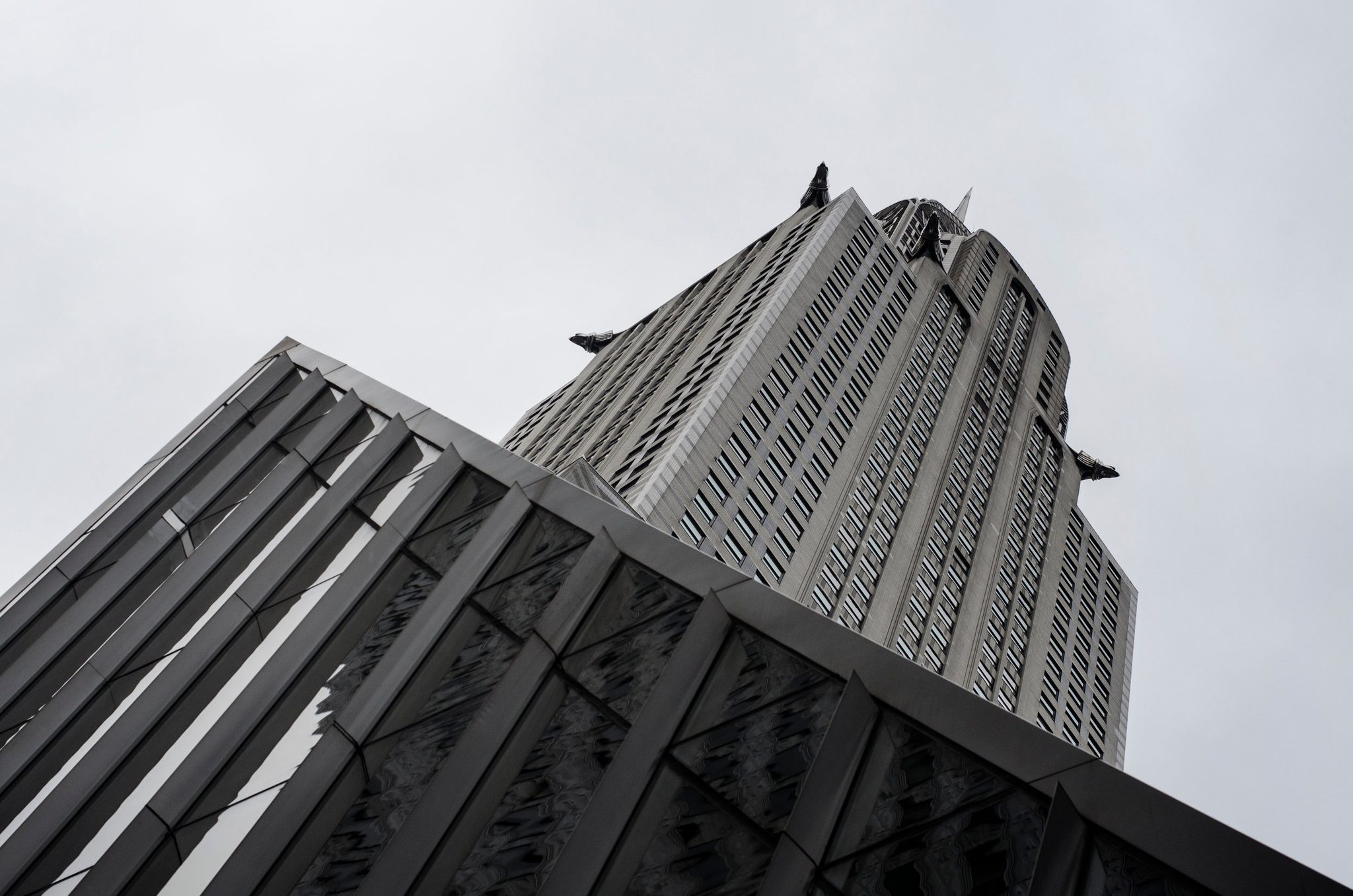 A tower's crown rises from a slope of steel and glass.