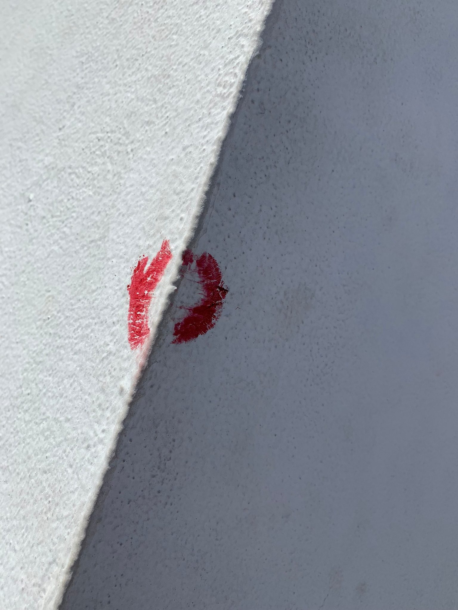A red lipstick kiss on a white wall.
