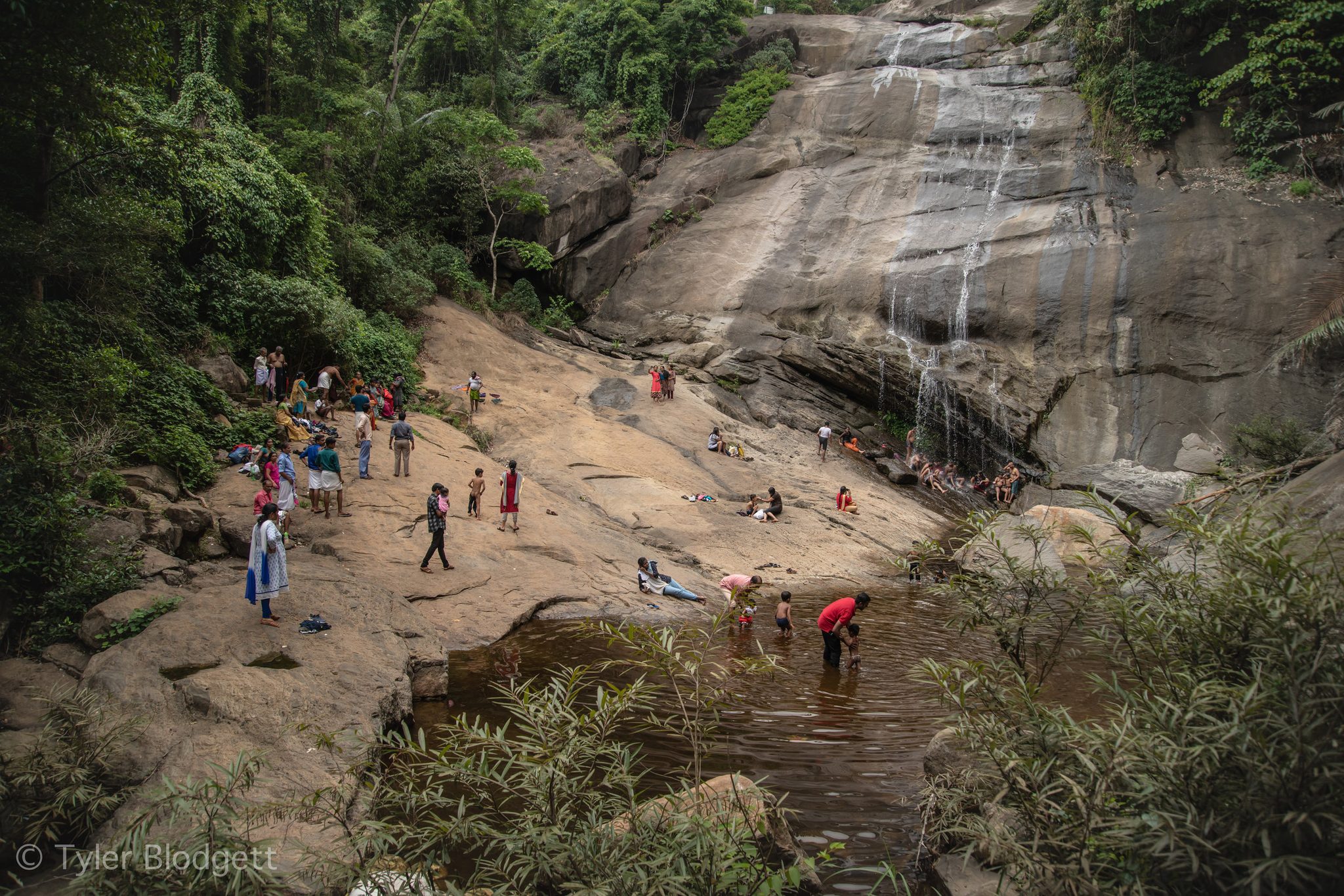 Families scatter across the granite below the falls, a few brave enough to wade into the pool.