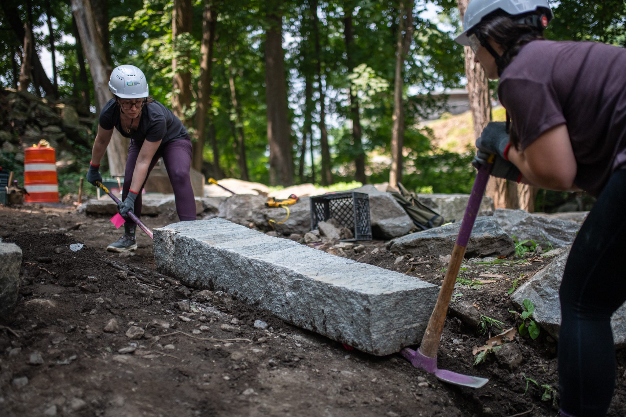She pries at the step while her partner digs beside it.