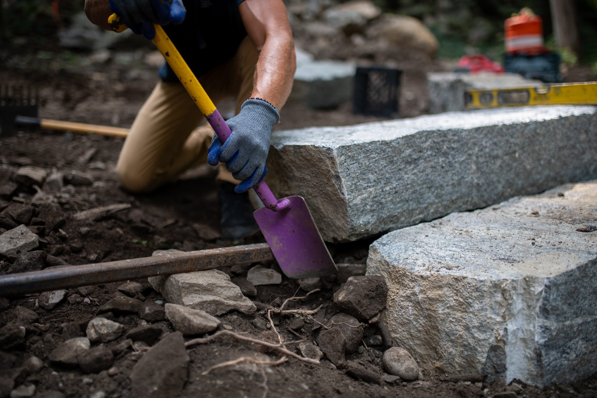 A trowel pushes gravel in beneath the step.