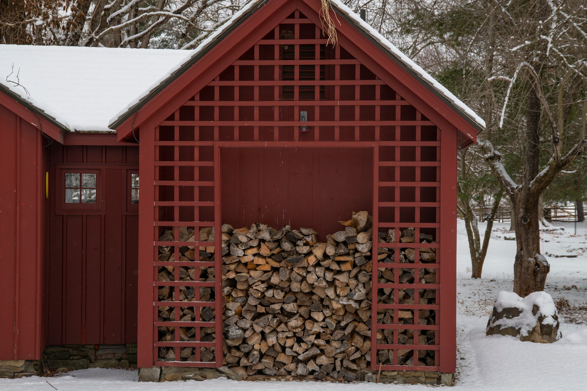 Snow on the roof, firewood stacked behind red lattice.