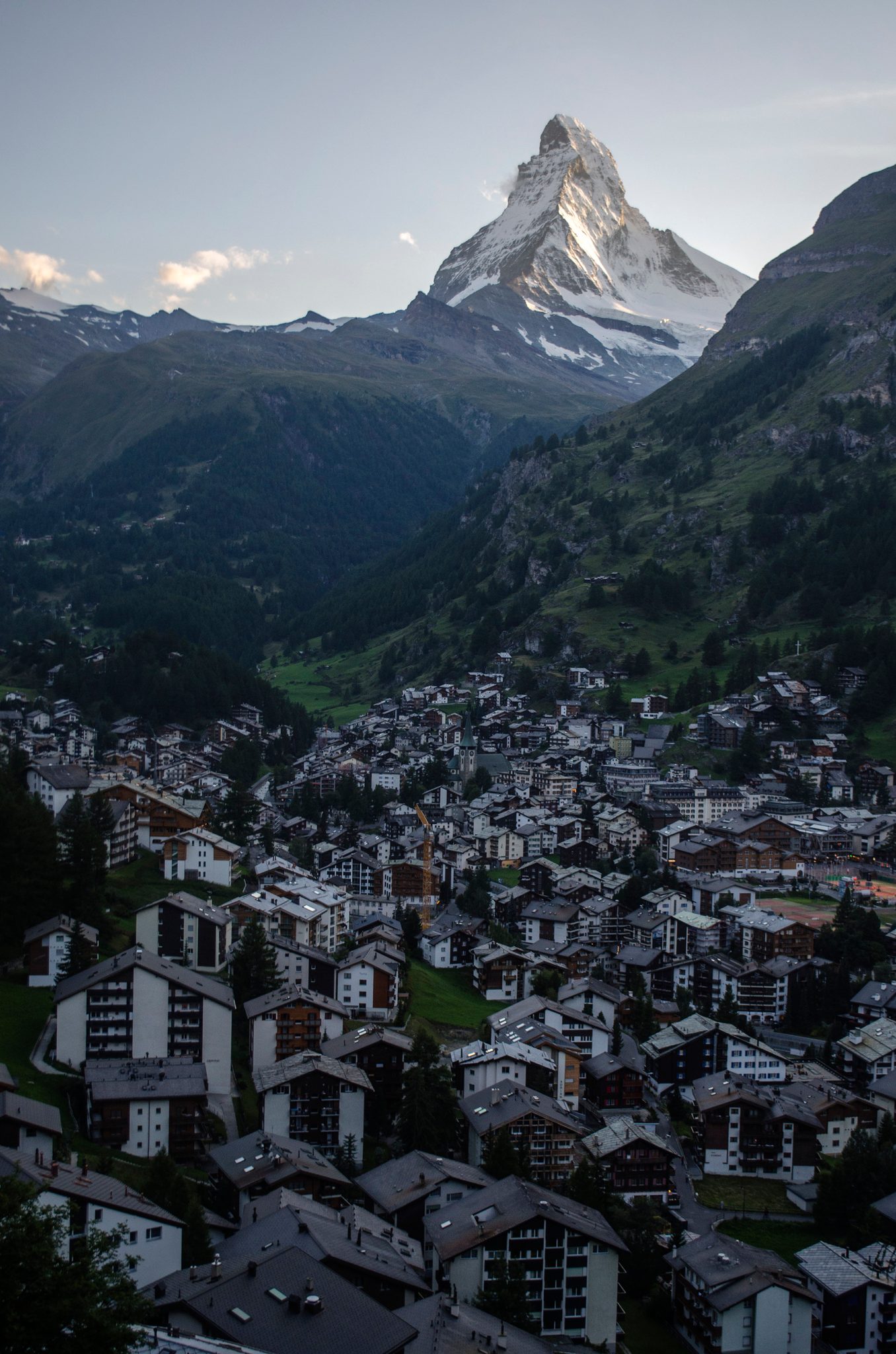 The Matterhorn stands over the rooftops of Zermatt as evening settles on the town.