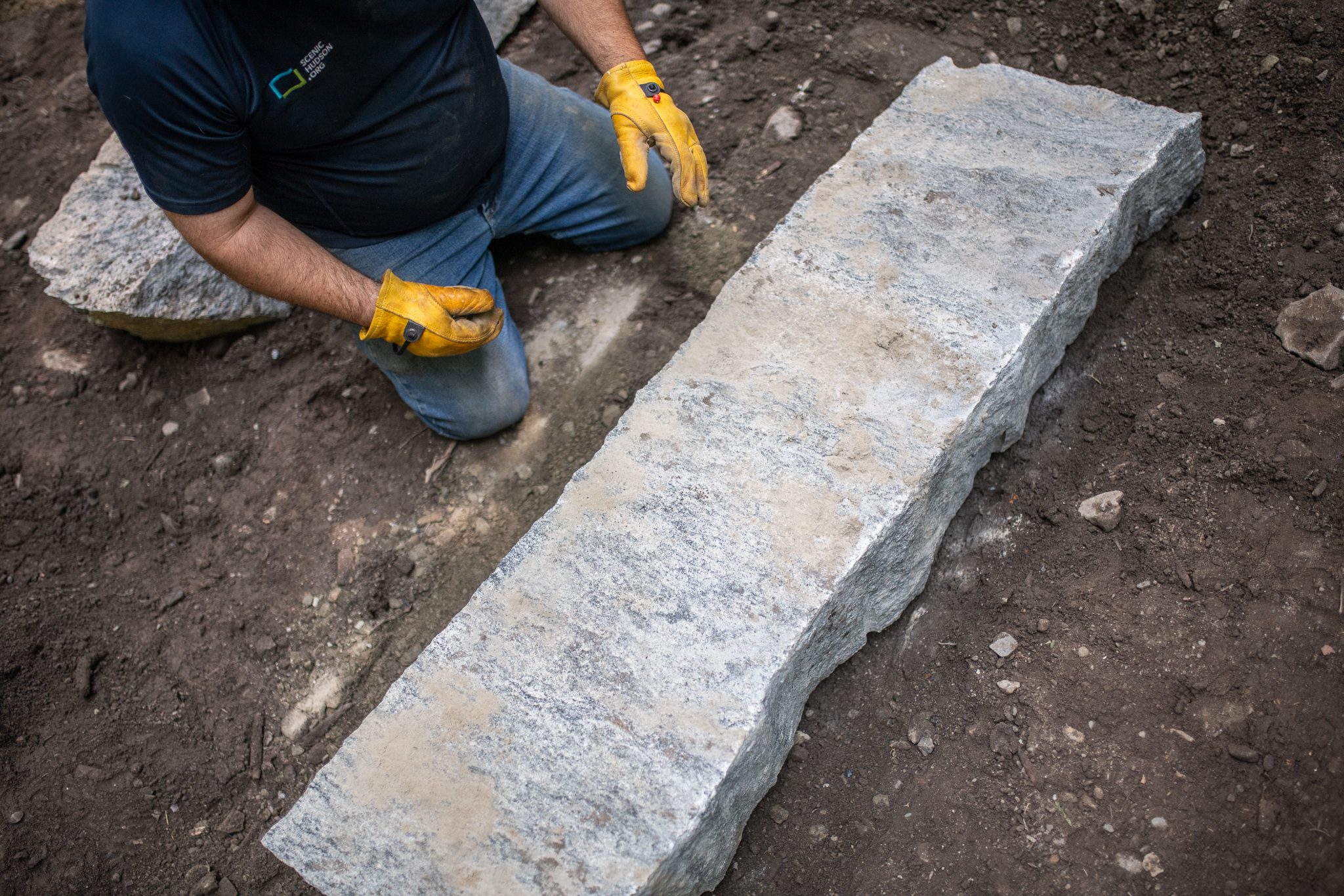 Kneeling beside a long granite step, he checks the fit.