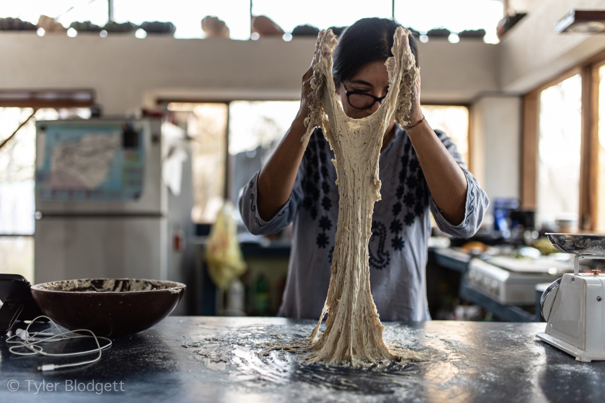 She lifts the dough high and lets it stretch.