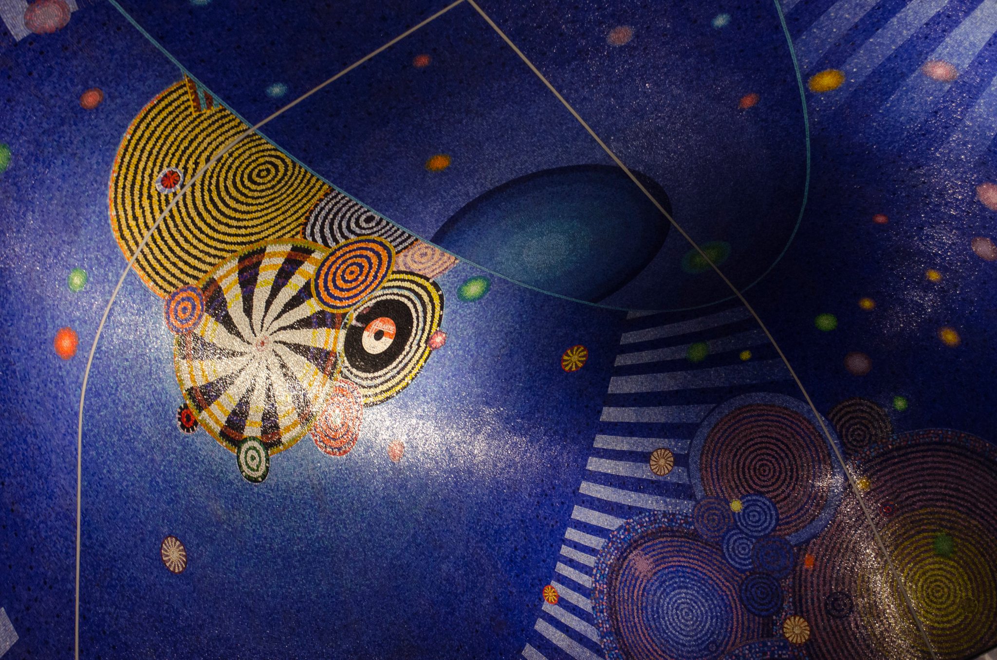 At 34th Street, a mosaic spins in blue and gold across the station wall.