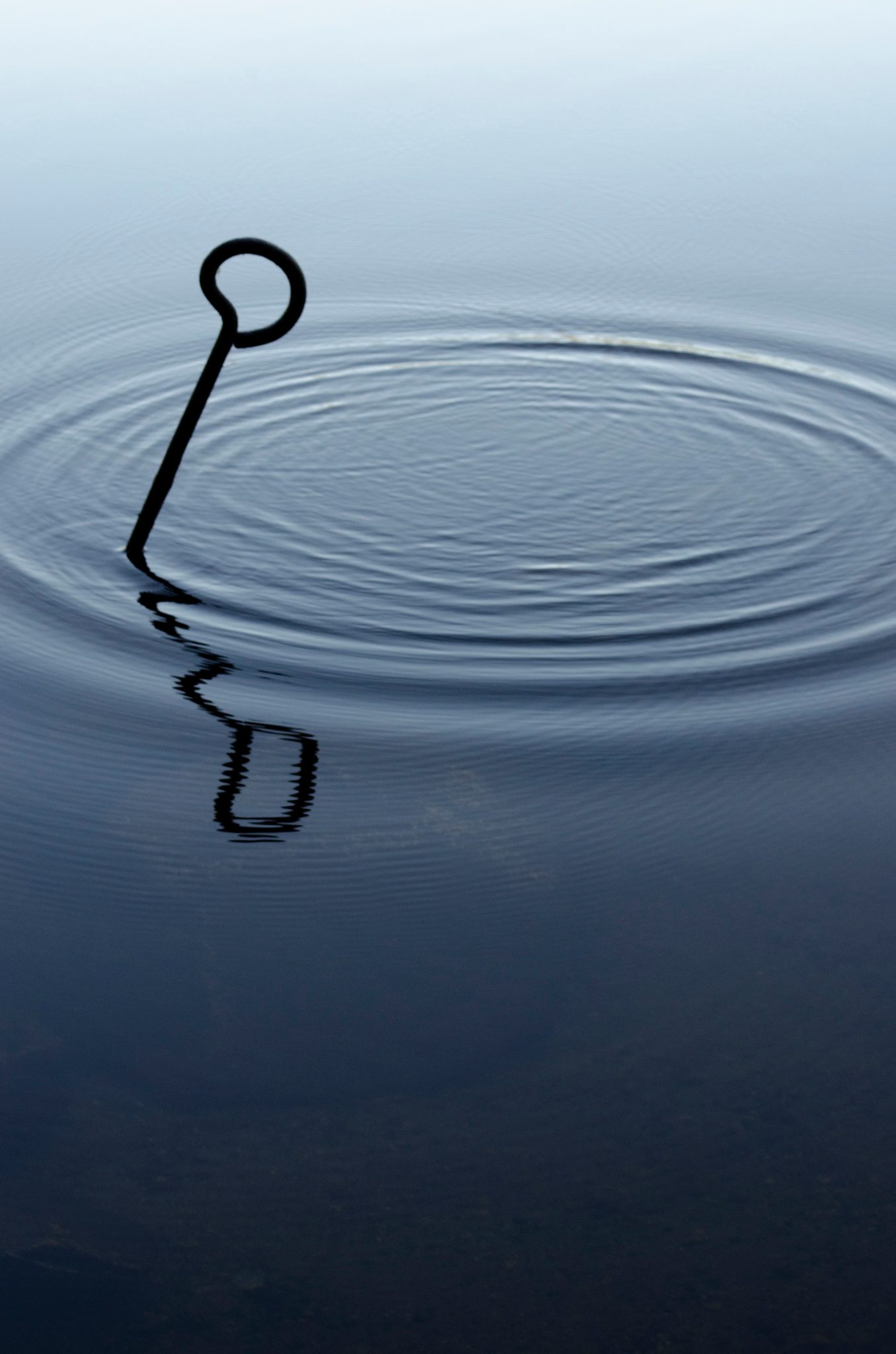 A mooring ring breaks the calm water into rings. Light cannot glisten without imperfections.