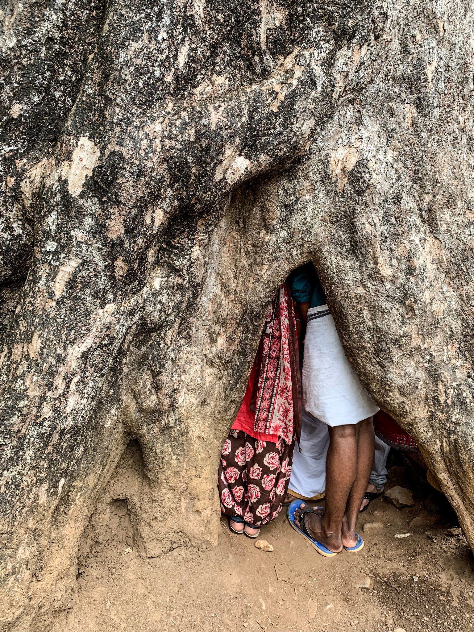 Someone squeezes through a narrow crack in the rock, sandaled feet and a bright sari the last things left in the light.
