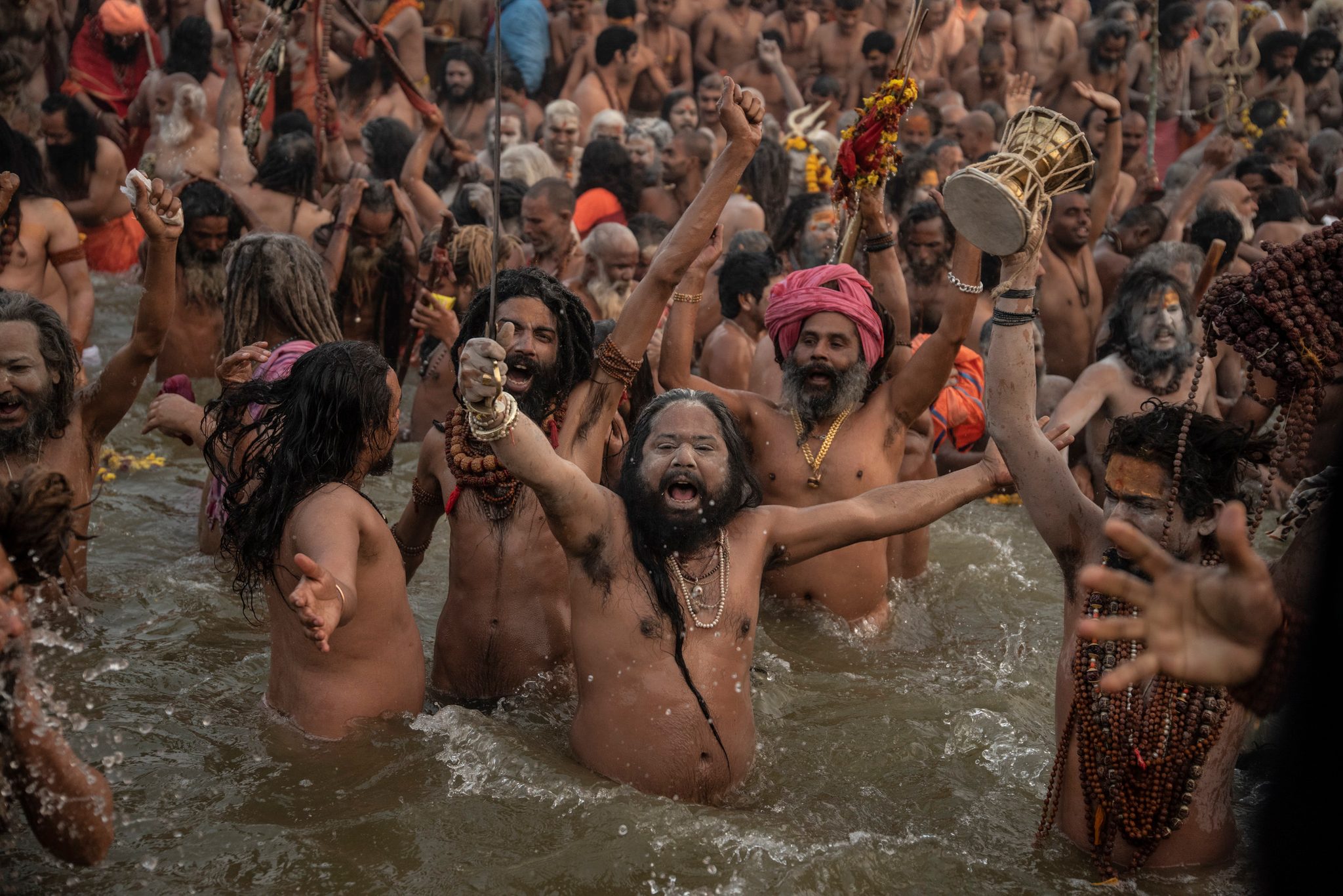 Arms flung wide, the sadhus roar as they plunge into the water.