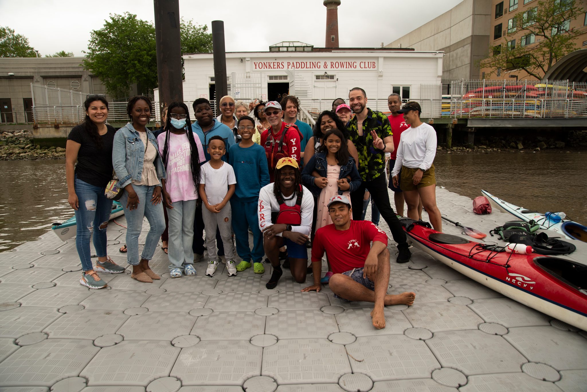 The whole group again in front of the paddling and rowing club, boats pulled up on the dock beside them.