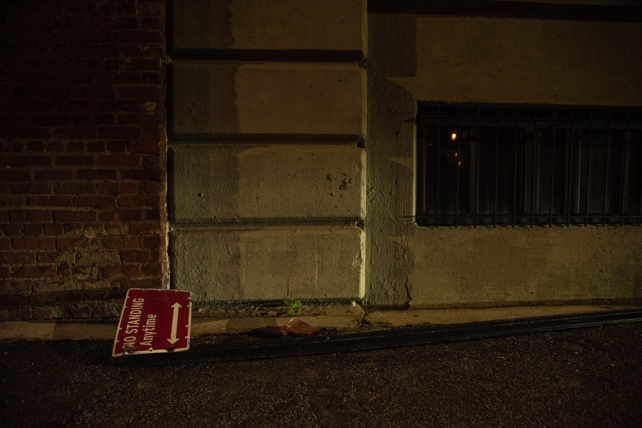 A No Standing Anytime sign lies flat on the ground, obeying itself.