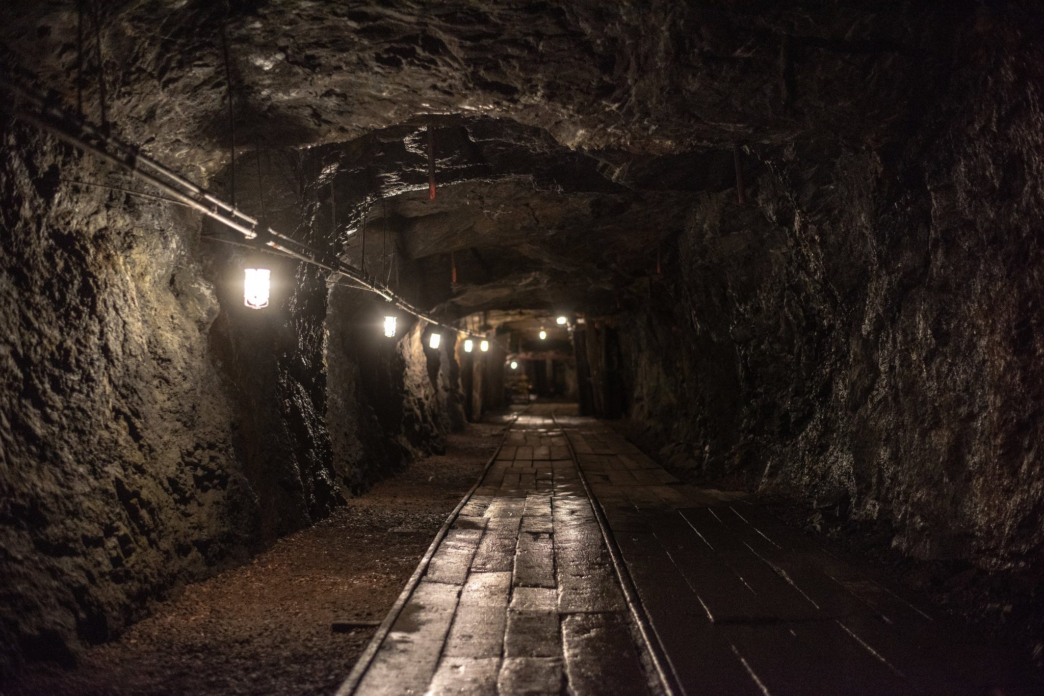 A string of bulbs lights the way down a rock-cut tunnel.